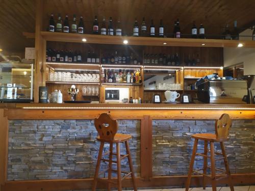 a bar with two wooden stools in front of it at Campeggio Beaulard in Beaulard