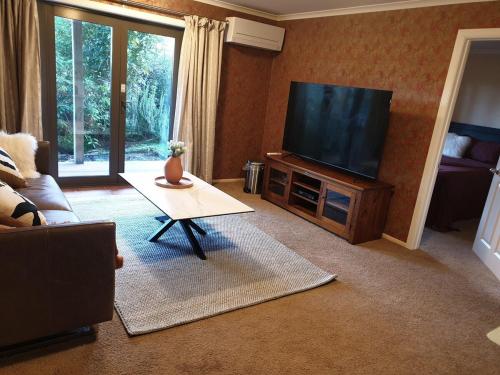 a living room with a flat screen tv and a table at Hidden Peace With Loved Ones in Dunedin
