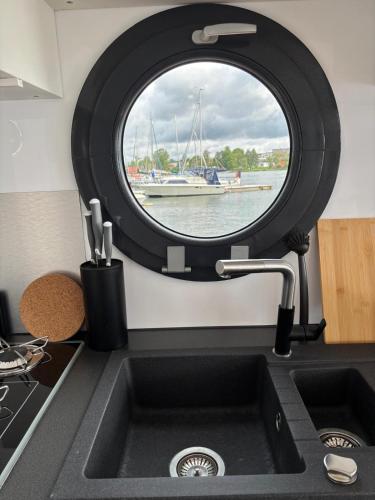 a kitchen sink with a round window above it at Houseboat -La Calma- Czaplinek in Czaplinek
