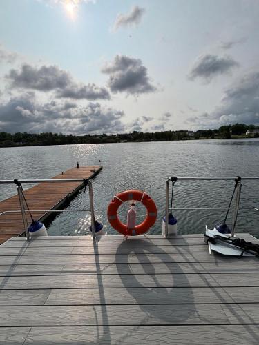 a dock with a red life preserver on the water at Houseboat -La Calma- Czaplinek in Czaplinek