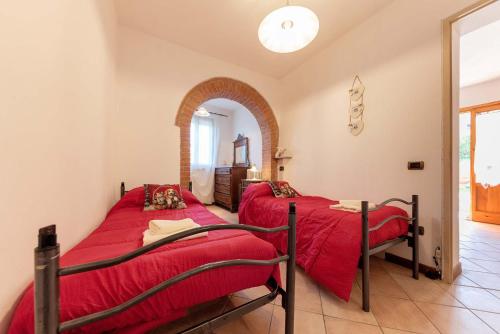 two beds in a room with red sheets at Il Glicine in Palaia