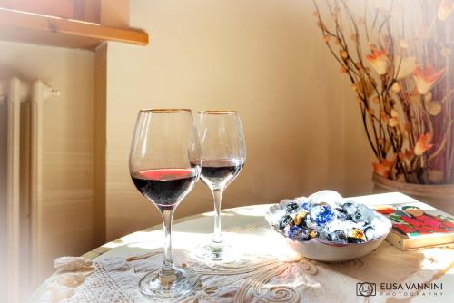 two wine glasses sitting on a table with a bowl of flowers at Il Glicine in Palaia
