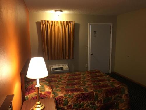 a hotel room with a bed and a lamp at Knights Inn Merrillville in Merrillville