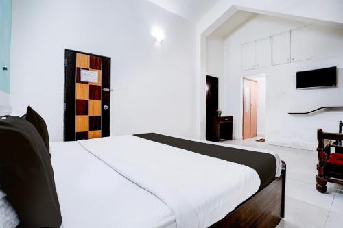 a bedroom with a white bed and a tv at Hotel O Benaulim Beach Goa in Goa