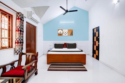 a bedroom with a bed and a chair at Hotel O Benaulim Beach Goa in Goa