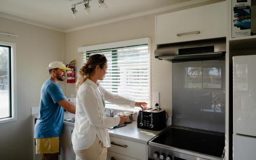 a man and a woman preparing food in a kitchen at Tasman Holiday Parks - Miranda in Miranda