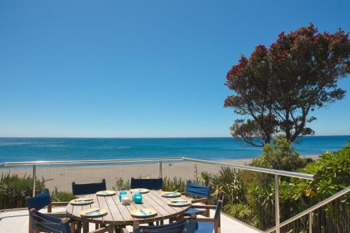 a table and chairs on a balcony with the beach at Beachfront Oakura - steps from stunning beach in Oakura
