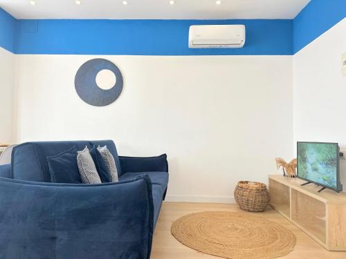 a living room with a blue couch and a clock at PROMO Elegant Apartments NEW - Colorful by the sea in Durrës
