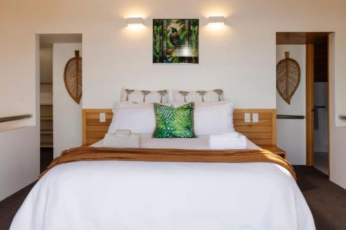 a bedroom with a large bed with white sheets at Beachfront Oakura - steps from stunning beach in Oakura
