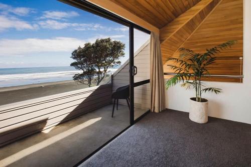 a room with a balcony with a view of the ocean at Beachfront Oakura - steps from stunning beach in Oakura