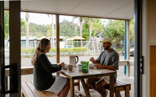 a man and a woman sitting at a table at Tasman Holiday Parks - Coromandel in Coromandel Town