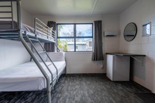a small room with two bunk beds and a window at Tasman Holiday Parks - Coromandel in Coromandel Town