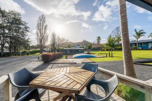 a wooden table and chairs on a deck at Tasman Holiday Parks - Coromandel in Coromandel Town