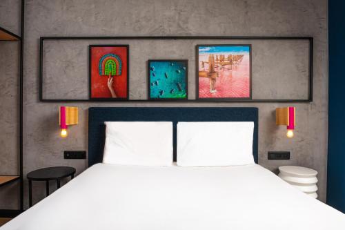 a bedroom with a white bed and paintings on the wall at Ibis Styles Dakar in Dakar