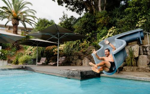 ein Mann, der in einem Schwimmbecken eine Rutsche hinunterrutscht in der Unterkunft Tasman Holiday Parks - Waihi Beach in Waihi Beach