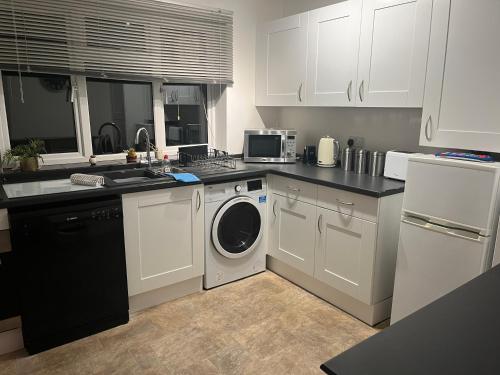 a kitchen with white cabinets and a washer and dryer at A Home from Home -2 Bed Flat & Free Driveway Parking in Ascot