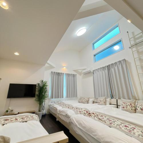 a bedroom with three beds and a tv and a window at アンドステイ野方2丁目 in Tokyo