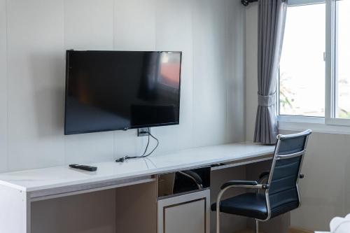 a desk with a television on a wall with a chair at TJ 4711 Residence in Maha Sarakham