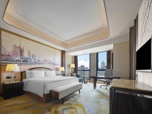 a bedroom with a bed and a desk and a piano at Wanda Vista Tianjin in Tianjin