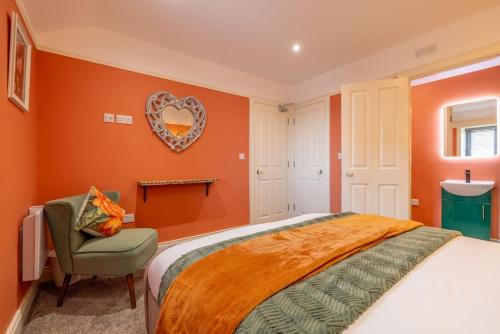 a bedroom with orange walls and a bed and a chair at Boutique Stays at 56B in Newtownards