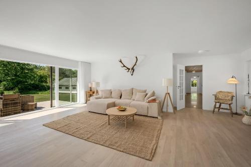 a living room with a white couch and a table at Lovely Holiday Home, Completely Renovated In 2025, In Quiet And Beautiful Surroundings in Sønder Felding