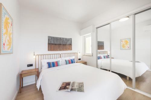 a white bedroom with a bed and a window at Equador Studios by Olala Homes in Cascais