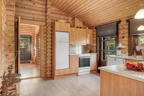 a kitchen with wooden cabinets and a white refrigerator at Well-Maintained Log House With Hot Tub, Sauna And Covered Terrace In Thy 