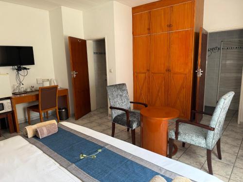 a living room with a table and chairs and a desk at Hotel Pension Steiner in Windhoek