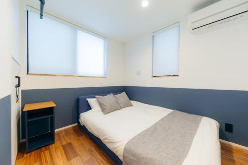a bedroom with a bed and two windows at UKIYO BLUE-羽田空港6分-品川駅7分-最大10名貸切一軒家-100inchスクリーン完備 in Tokyo