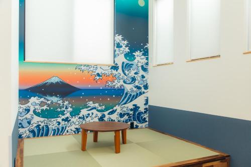 a table in a room with a mural of a wave at UKIYO BLUE-羽田空港6分-品川駅7分-最大10名貸切一軒家-100inchスクリーン完備 in Tokyo