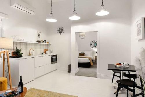 a white kitchen with a table and a bedroom at Apartment 22 - stylish retreat in central location in Fitzroy