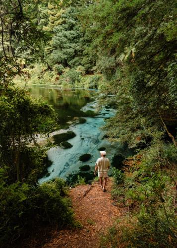 a man walking down a path next to a river at Tasman Holiday Parks - Rotorua in Rotorua