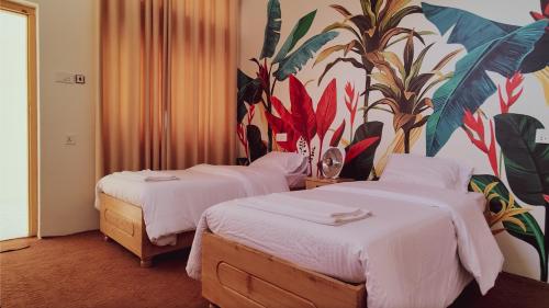 two beds in a hotel room with a mural on the wall at Askari Inn Hotels in Madyan