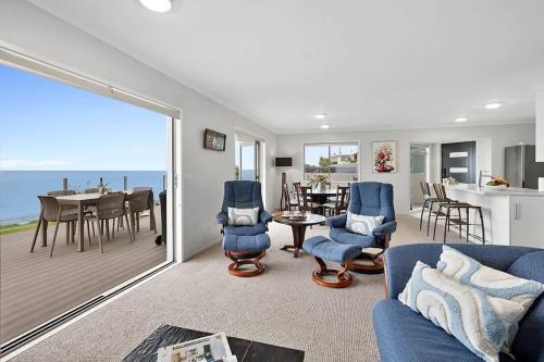 a living room with a blue couch and a dining room at Beachfront Breeze - sea views for days in New Plymouth