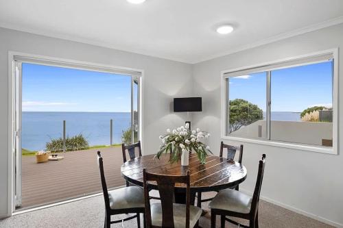 a dining room with a table and a view of the ocean at Beachfront Breeze - sea views for days in New Plymouth