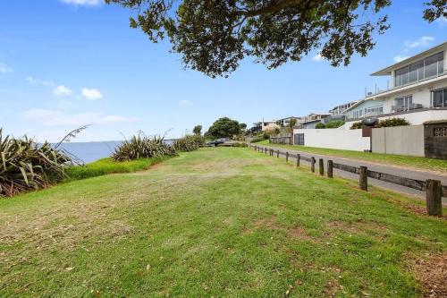 a dirt road with a fence and a grass field at Beachfront Breeze - sea views for days in New Plymouth