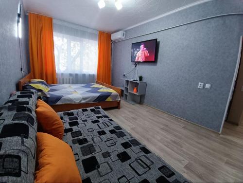 a bedroom with a bed and a flat screen tv at Комфортная квартира Сабитовой 23а, район ЖД вокзал in Balqash