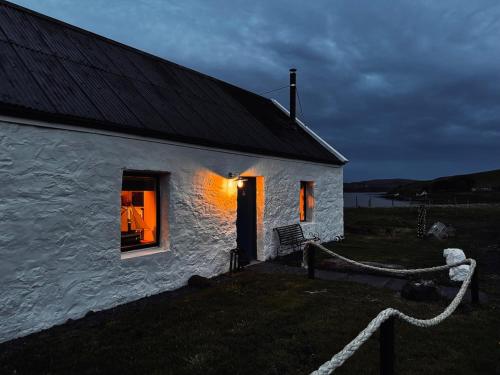 a white house with a light in the window at The Captain's Place - Isle of Skye in Bracadale