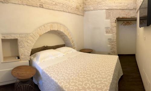 a bedroom with a white bed with a brick wall at La Cummersa Trulli Holiday in Alberobello