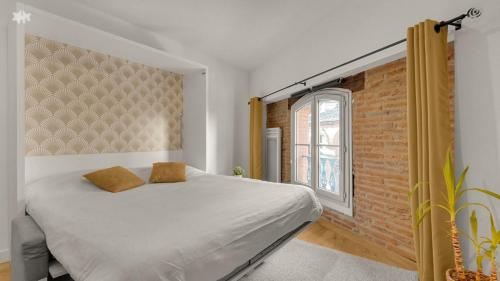 une chambre avec un lit et un mur de briques dans l'établissement Le Floral - Parking privé - Climatisation, à Toulouse