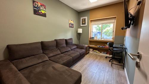 a living room with a brown couch and a window at Refreshed apartment with private garden in Almada