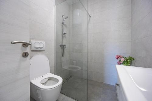 a white bathroom with a toilet and a shower at NU Sea View in Podstrana