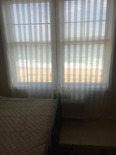 a bedroom with two windows with white curtains and a bed at Misquamicut Beach Front Inn in Misquamicut