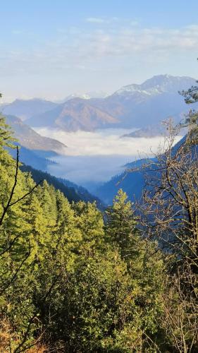 a view of a mountain valley with clouds in the distance at Baserah Stay & Cafe in Mandi