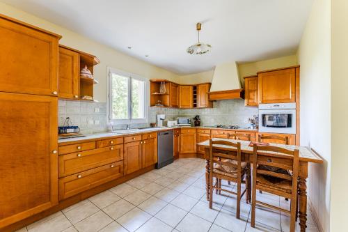 a kitchen with wooden cabinets and a table and chairs at Villa Les Tamaris 8 Personnes in La Teste-de-Buch