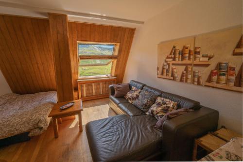 uma sala de estar com um sofá de couro e uma janela em Apartamentos Formigal em Formigal