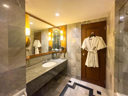 a bathroom with a sink and a robe hanging on a door at Rembrandt Hotel Bangkok in Bangkok