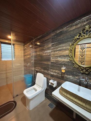a bathroom with a toilet and a sink and a mirror at Misty Palace Luxury Villa by Natura Stays in Lonavala