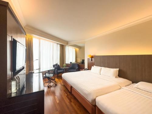 a hotel room with two beds and a television at Rembrandt Hotel Bangkok in Bangkok