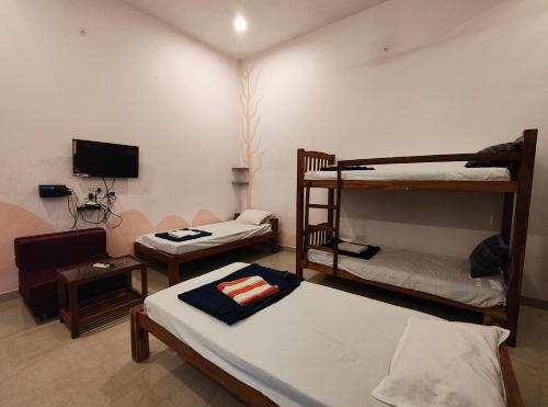 a room with two bunk beds and a tv at Art Le Cafe in Auroville